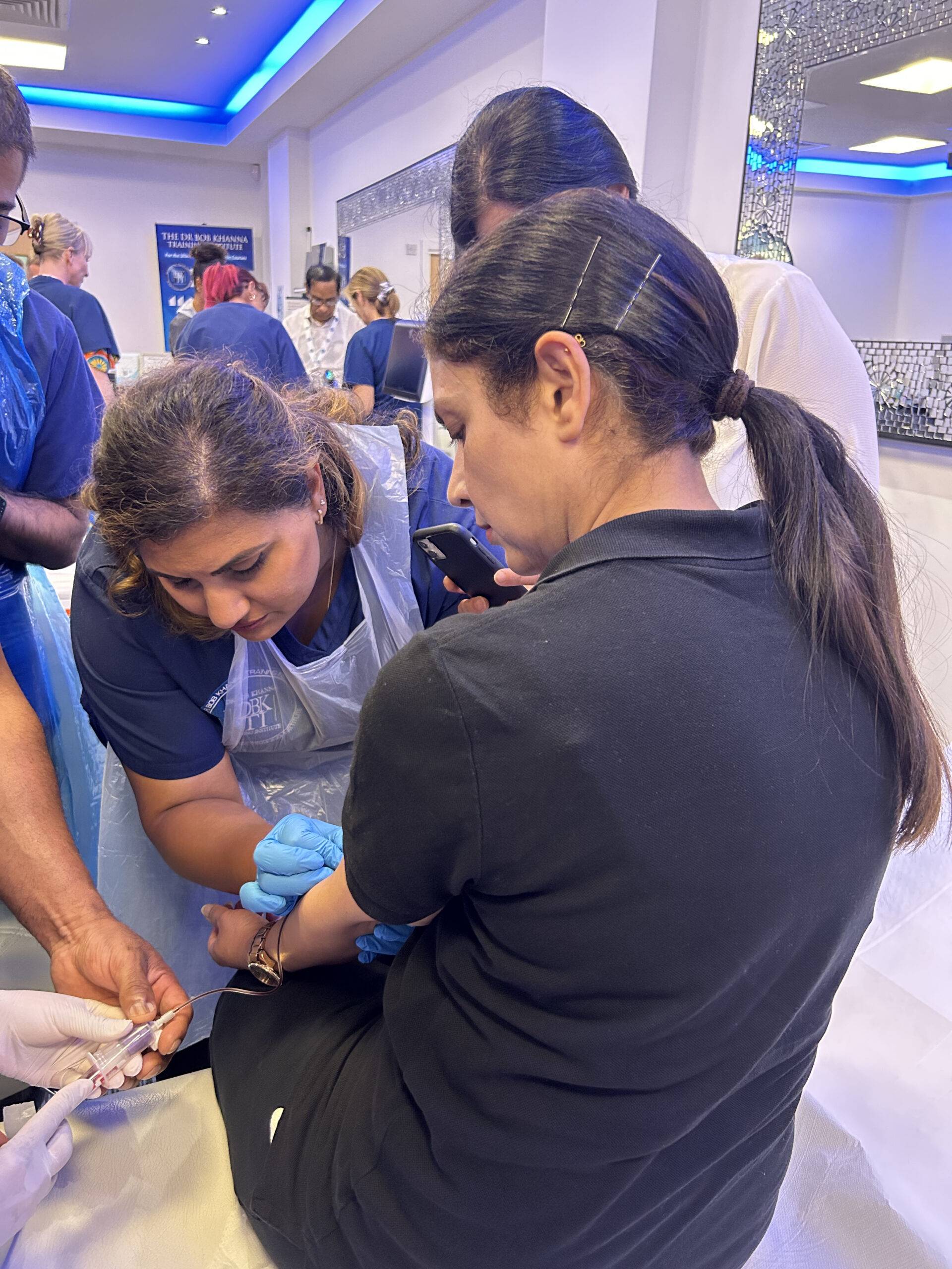 Image of a woman collecting blood from a patients arm for PRP