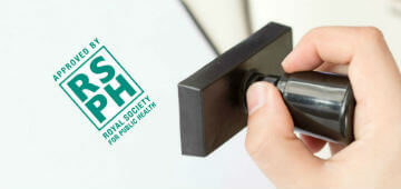 RSPH Green Stamp being stamped on paper 