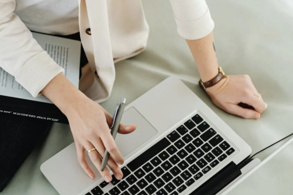 woman sat at a laptop with a pen in her hand