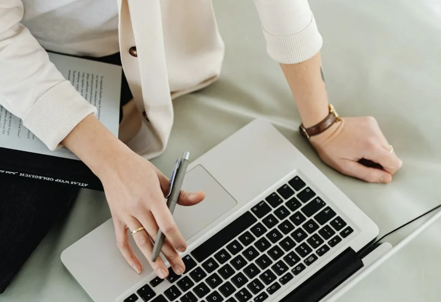 woman sat at a laptop with a pen in her hand